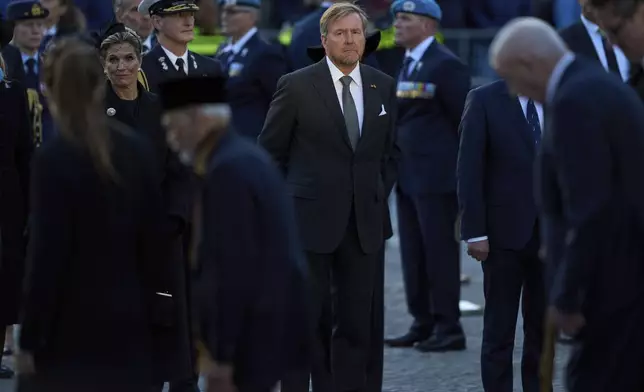 A ray of light shines on Dutch King Willem-Alexander, as Queen Maxima stands left, after laying a wreath during a solemn annual national service to commemorate the war dead in Amsterdam, Netherlands, Sunday, May 4, 2025. (AP Photo/Peter Dejong)