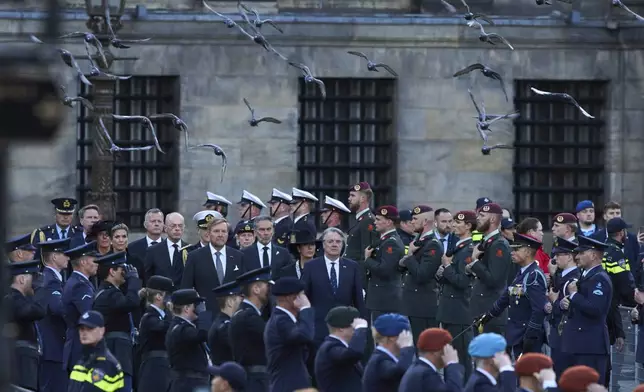 Pigeons fly as Dutch King Willem-Alexander and Queen Maxima arrive to lay a wreath during a solemn annual national service to commemorate the war dead in Amsterdam, Netherlands, Sunday, May 4, 2025. (AP Photo/Peter Dejong)