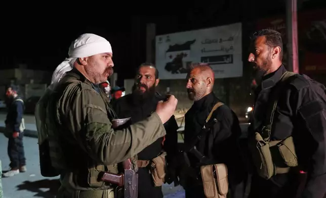A Druze gunman, left, speaks with Syrian security forces who reached a deal with Druze gunmen to deploy around the southern Damascus suburb of Jaramana that has witnessed fighting earlier this week in Damascus, Syria, early Friday, May 2, 2025. (AP Photo/Omar Sanadiki)