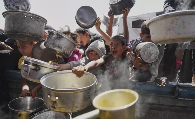 Palestinian children struggle to get donated food at a community kitchen in Khan Younis, Gaza Strip, Saturday, May 3, 2025. (AP Photo/Abdel Kareem Hana)