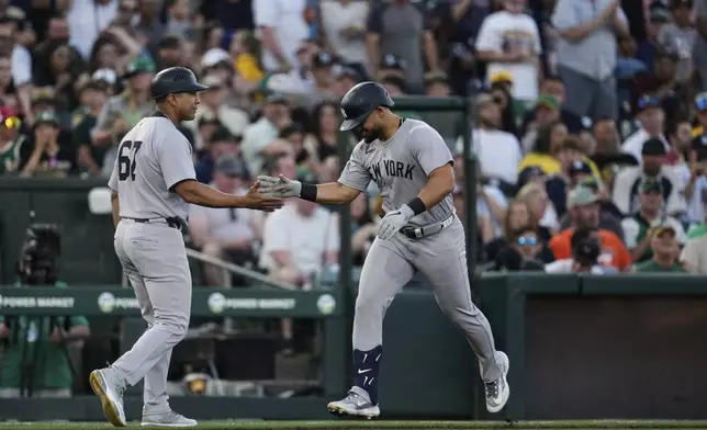 New York Yankees' Jasson Domínguez, right, celebrates with third base coach Luis Rojas after hitting a solo home run during the third inning of a baseball game against the Athletics, Friday, May 9, 2025, in West Sacramento, Calif. (AP Photo/Godofredo A. Vásquez)