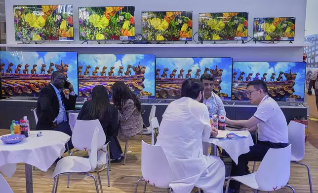 FILE - Visitors talk to a sale rep for televisions at the 137th Canton Fair, in Guangzhou in southern China's Guangdong province on April 15, 2025. (AP Photo/Ng Han Guan, Filer)