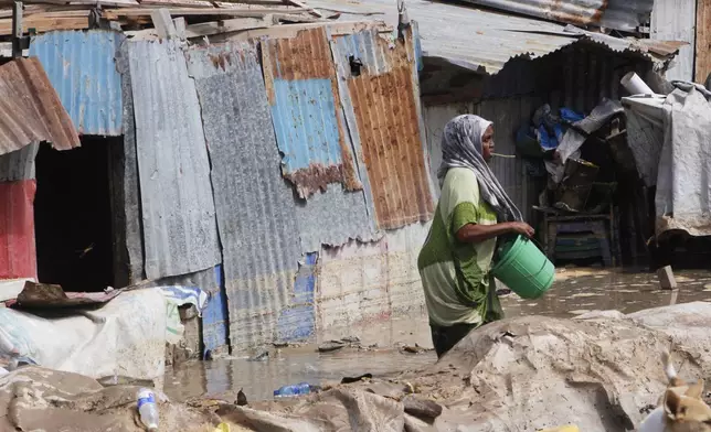 A woman stands in front of her flooded house following a heavy downpour in Mogadishu, Somalia, Saturday, May 10, 2025. (AP Photo/Farah Abdi Warsameh)