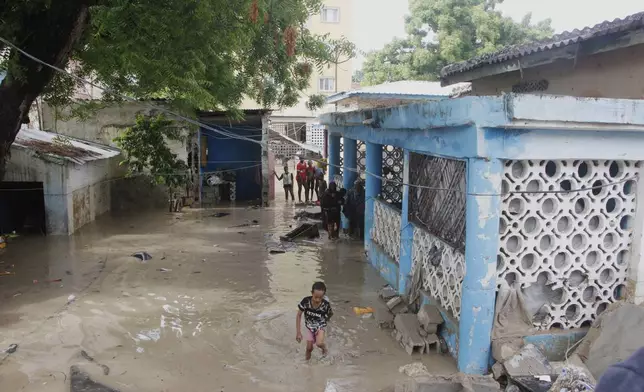 People stand in front of their flooded house following a heavy downpour in Mogadishu, Somalia, Saturday, May 10, 2025. (AP Photo/Farah Abdi Warsameh)