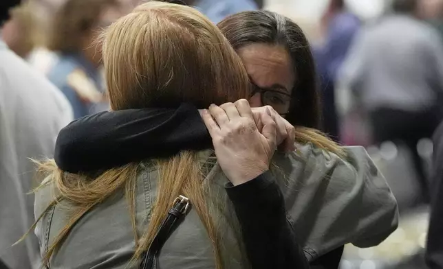 People hug at the Jewish Community Center of Greater Kansas City before a vigil for Sarah Milgrim and Yaron Lischinsky, Israeli Embassy staff members who were shot and killed while leaving an event at a Jewish museum in Washington, Thursday, May 22, 2025, in Overland Park, Kan. (AP Photo/Charlie Riedel)