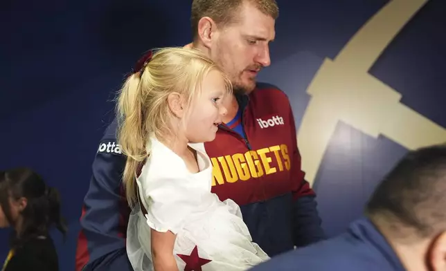 Denver Nuggets center Nikola Jokic holds his daughter after Game 7 of an NBA basketball first-round playoff series against the Los Angeles Clippers, Saturday, May 3, 2025, in Denver. (AP Photo/David Zalubowski)