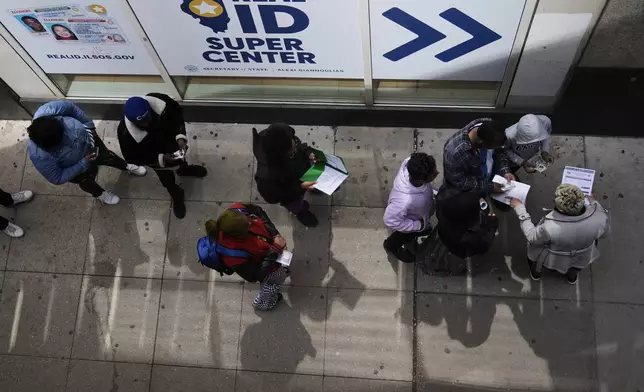 An employee, right, checks on necessary documents as people line up to apply for Real ID at a Real ID Supercenter in downtown Chicago, Tuesday, May 6, 2025. (AP Photo/Kiichiro Sato)
