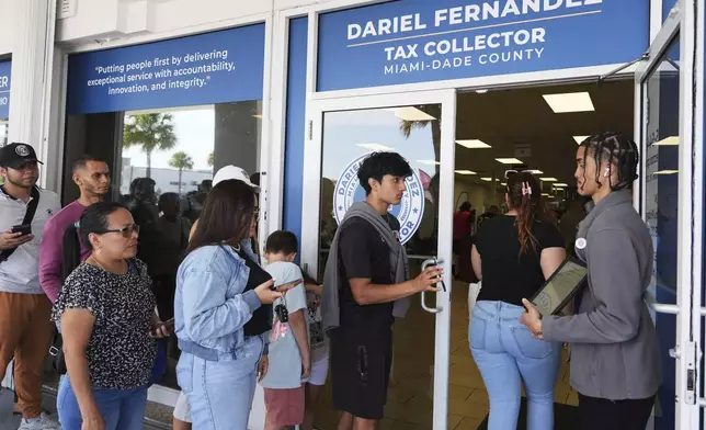 Customer Service representative Marlon Suarez, right, monitors the doorway outside of a Miami-Dade County Office of the Tax Collector Tuesday, May 6, 2025, in Miami. (AP Photo/Lynne Sladky)