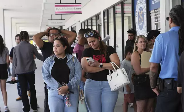 People stand in line outside of a Miami-Dade County Office of the Tax Collector Tuesday, May 6, 2025, in Miami. (AP Photo/Lynne Sladky)