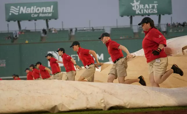 Grounds crew members race to cover the infield during a rain delay of a baseball game between the Boston Red Sox and the Minnesota Twins, Saturday, May 3, 2025, in Boston. (AP Photo/Robert F. Bukaty)