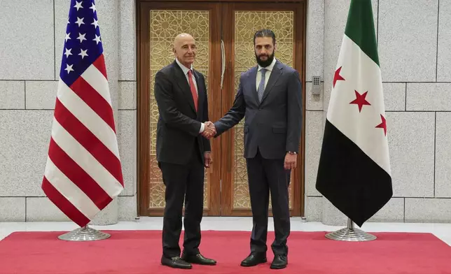 In this photo released by the Syrian official news agency SANA, Syria's interim President Ahmad al-Sharaa, right, shakes hands with U.S. Ambassador to Turkey and Special Envoy to Syria Tom Barrack, in Damascus, Syria, May 29, 2025. (SANA via AP)