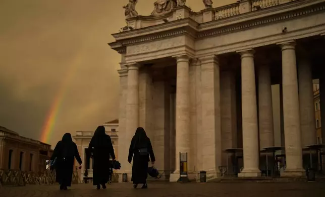 Nuns walk along St. Peter's Square after rain during the fourth of nine days of mourning for late Pope Francis, at the Vatican, Tuesday, April 29, 2025. (AP Photo/Francisco Seco)