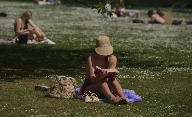 A woman reads on a sunny day at a park in London, Wednesday, April 30, 2025. (AP Photo/Kin Cheung)
