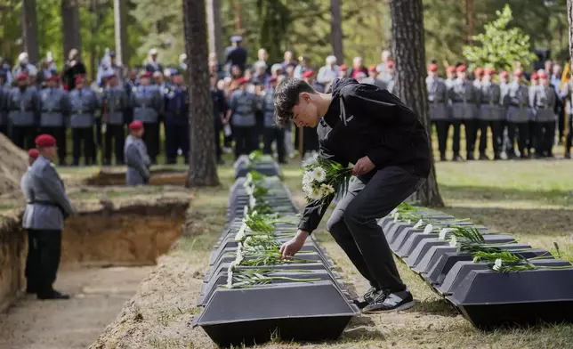 A student pays tribute to the the remains of fallen German soldiers of WWII during a funeral service at a memorial site for fallen soldiers in Halbe, Germany, Wednesday, April 30, 2025. (AP Photo/Ebrahim Noroozi)