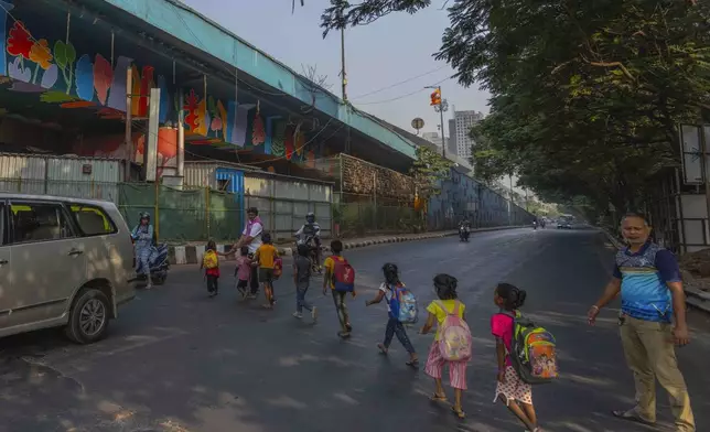 Children form a line as they cross a busy highway to reach the Signal Shala school in Thane near Mumbai, India, April 5, 2025. (AP Photo/Rafiq Maqbool)