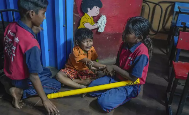 A girl comforts a young boy who fell while playing at the Signal Shala school in Thane near Mumbai, India, April 5, 2025. (AP Photo/Rafiq Maqbool)