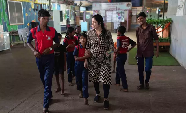 Teacher Shaila Desale, center, walks with her students during a break at the Signal Shala school in Thane near Mumbai, India, April 9, 2025. (AP Photo/Rafiq Maqbool)