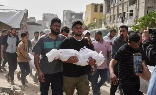 Saleh Zenati, carries the body of his infant nephew Khalid Zenati killed in an Israeli army airstrike, during his funeral in Khan Younis, Gaza Strip, Sunday, May 18, 2025. (AP Photo/Abdel Kareem Hana)
