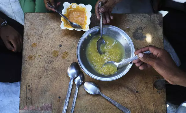 The Al-Arja family eats lentil soup inside their tent in a camp for displaced Palestinians in Muwasi, Khan Younis, Gaza, Wednesday, May 21, 2025. (AP Photo/Abdel Kareem Hana)