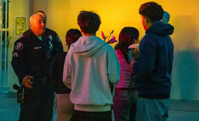 Students speak to the Santa Ana Police about setting up a makeshift memorial outside Santa Ana High School in Santa Ana, Calif. on Wednesday, May 7, 2025, after a stabbing on campus shortly after the school day ended. (Leonard Ortiz/The Orange County Register via AP)