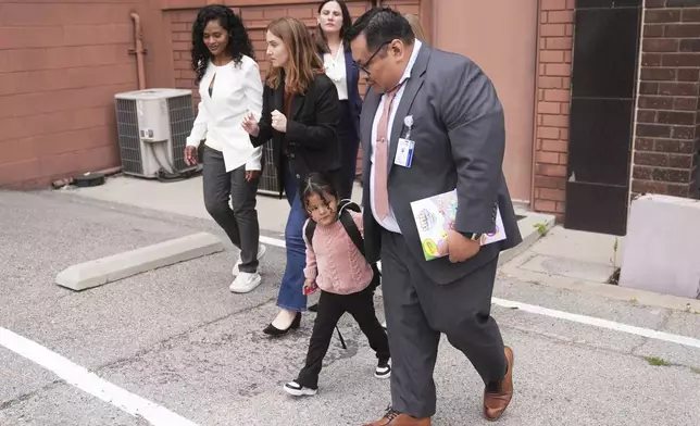 A 4-year-old Mexican girl, who has short bowel syndrome, holds the hand of Yonny Aguilar, a senior paralegal at Public Counsel, as she and her mother, far left, leave a news conference in Los Angeles, Wednesday, May 28, 2025, after their humanitarian parole was terminated and they were ordered to self-deport. (AP Photo/Jae C. Hong)