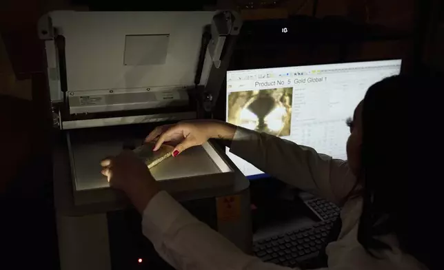 Sarahi Cervantes places a gold bar on an X-ray machine for assaying at A&amp;M Precious Metals in the St. Vincent Jewelry Center in the Jewelry District of Los Angeles, Friday, May 2, 2025. (AP Photo/Jae C. Hong)