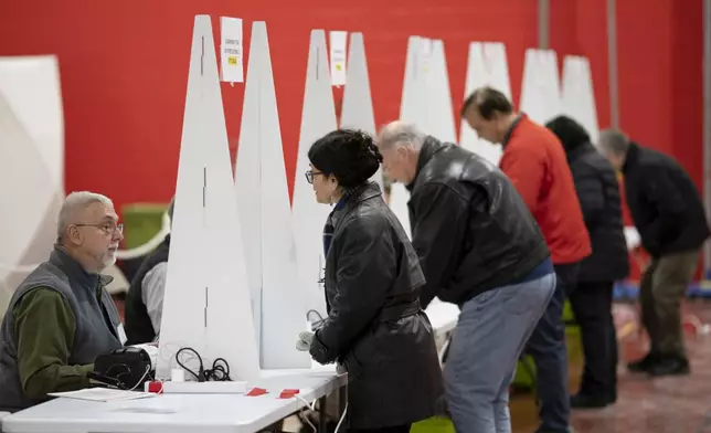 FILE - Voters check in to cast ballots in the New Hampshire presidential primary at a polling site in Derry, N.H., Jan. 23, 2024. (AP Photo/David Goldman, File)