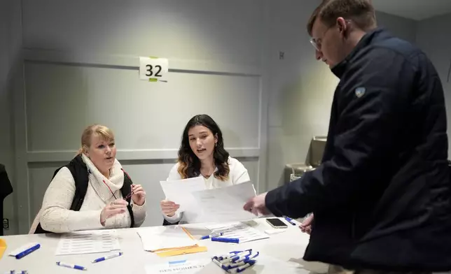 FILE - A caucus voter signs in at precinct 32 at Franklin Junior High in Des Moines, Iowa, Jan. 15, 2024. (AP Photo/Carolyn Kaster, File)