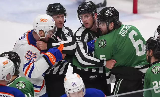Edmonton Oilers right wing Vasily Podkolzin (92) and Dallas Stars defenseman Lian Bichsel (6) have to be restrained by linesmen Devin Berg (87) and Bevan Mills (53) during the third period in Game 2 of the Western Conference finals in the NHL hockey Stanley Cup playoffs, Friday, May 23, 2025, in Dallas. (AP Photo/LM Otero)