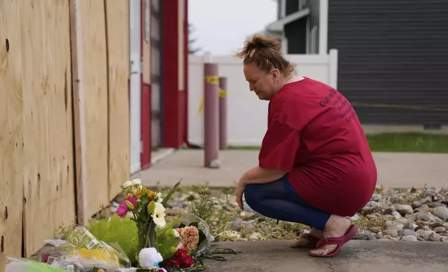 Brandy Fletcher leaves flowers at the scene after a car barreled through a building used for an after-school camp Tuesday, April 29, 2025, in Chatham, Ill. (AP Photo/Erin Hooley)