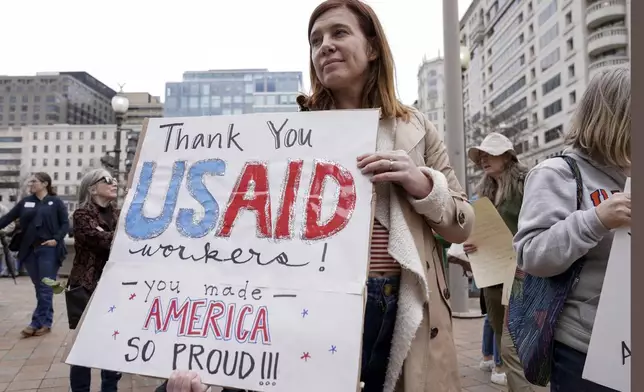 FILE - A person carries a sign in support of the United States Agency for International Development (USAID) workers, as they carry their personal belongings after retrieving them from the USAID's headquarters in Washington, Feb. 27, 2025. (AP Photo/Jose Luis Magana, File)