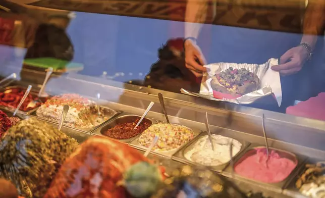 A vendor prepares the popular Turkish stuffed baked potato dish known as "Kumpir" at a waterfront square in Ortakoy, Istanbul, Turkey, Friday, May 23, 2025. (AP Photo/Emrah Gurel)