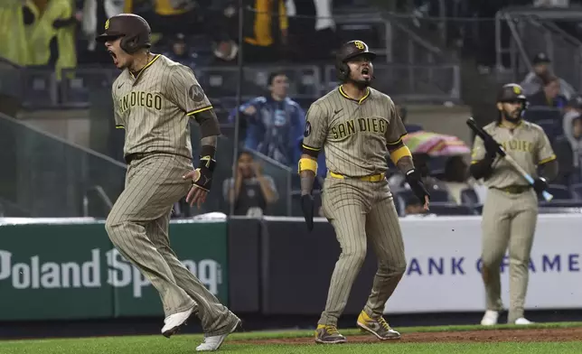 San Diego Padres' Manny Machado, left, and Luis Arraez, center, react after scoring on a single hit by Xander Bogaerts during the eighth inning of a baseball game against the New York Yankees, Monday, May 5, 2025, in New York. (AP Photo/Pamela Smith)