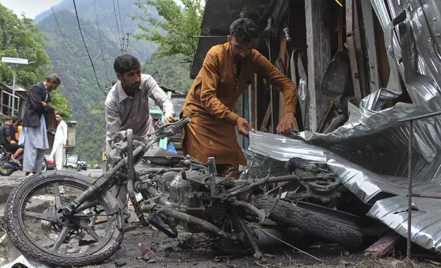 Local residents remove a burnt motorbike from near their shops damaged by Indian shelling, at the main bazaar, a day after the ceasefire between India and Pakistan was announced, near Jura, on the Line of Control, in Neelum Valley, a district of Pakistan's administered Kashmir, Sunday, May 11, 2025. (AP Photo/Ishfaq Hussain)