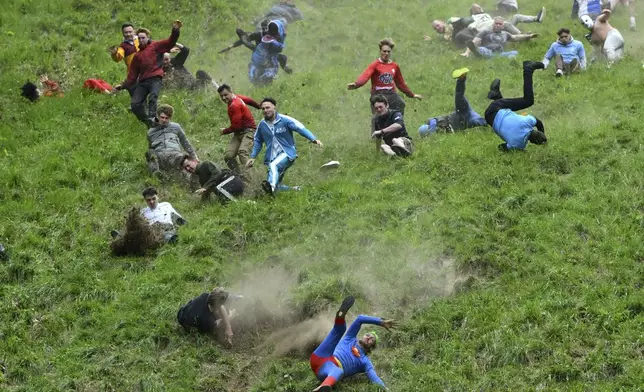 Participants compete in the men's downhill race category of the traditional annual Cheese Rolling contest at Cooper's Hill in Brockworth, Gloucestershire, England, Monday, May 26, 2025.(AP Photo/Anthony Upton)