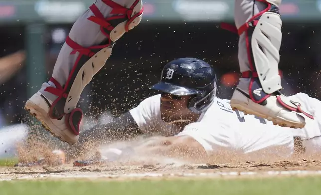 Detroit Tigers third base Andy Ib·Òez slides safely into home plate under Cleveland Guardians catcher Austin Hedges in the fourth inning during a baseball game, Sunday, May 25, 2025, in Detroit. (AP Photo/Paul Sancya)