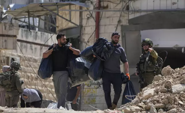Israeli soldiers check the identification cards of residents of the now evacuated Palestinian refugee camp of Tulkarem who return to collect belongings before the destruction of their homes as Israeli forces prepared to carry out the demolition of homes across the two refugee camps of the Israeli occupied West Bank city of Tulkarem, Thursday, May 29, 2025. (AP Photo/Nasser Nasser)