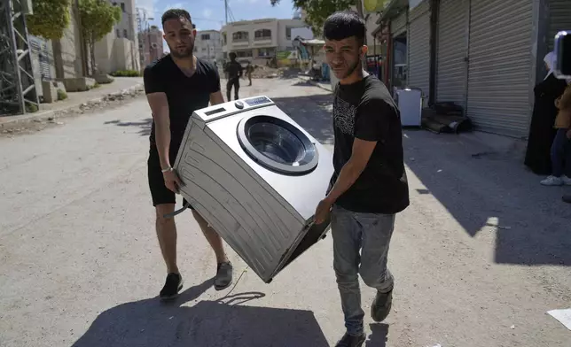 Residents of the now evacuated Palestinian refugee camp of Tulkarem who return to collect belongings before the destruction of their homes as Israeli forces prepared to carry out the demolition of homes across the two refugee camps of the Israeli occupied West Bank city of Tulkarem, Thursday, May 29, 2025. (AP Photo/Nasser Nasser)