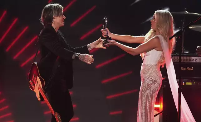 Megan Moroney, right, presents the triple crown award to Keith Urban during the 60th annual Academy of Country Music Awards on Thursday, May 8, 2025, in Frisco, Texas. (AP Photo/Chris Pizzello)
