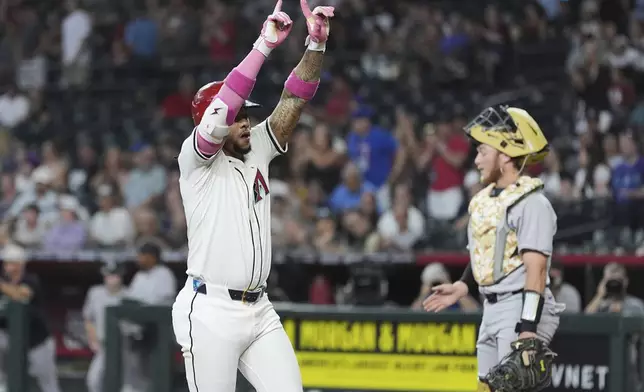 Arizona Diamondbacks' Ketel Marte, left, celebrates his home run as Colorado Rockies catcher Hunter Goodman pauses at home plate during the first inning of a baseball game Sunday, May 18, 2025, in Phoenix. (AP Photo/Ross D. Franklin)