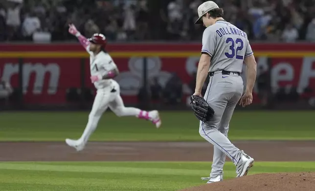 Colorado Rockies starting pitcher Chase Dollander (32) walks off the pitcher's mound after giving up a home run to Arizona Diamondbacks' Ketel Marte, left, during the first inning of a baseball game Sunday, May 18, 2025, in Phoenix. (AP Photo/Ross D. Franklin)