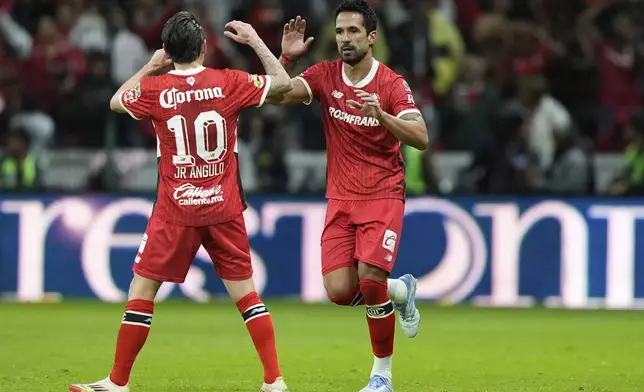 Toluca's Luan Garcia, right, is congratulated after scoring his side's opening goal against America during the Mexican soccer league second leg final match at Nemesio Diez stadium in Toluca, Mexico, Sunday, May 25, 2025. (AP Photo/Fernando Llano)