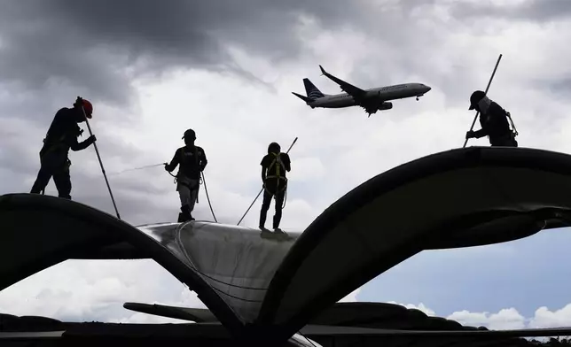 Workers clean a roof at the Tocumen International Airport in Panama City, Thursday, May 22, 2025, as Panama and Venezuela prepare to resume commercial flights nearly a year after suspending them when Panamanian President Jose Raul Mulino refused to recognize the re-election of Venezuelan President Nicolas Maduro. (AP Photo/Matias Delacroix)