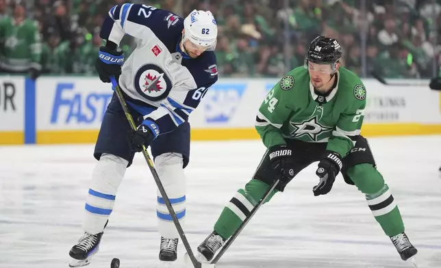 Winnipeg Jets' Nino Niederreiter (62) and Dallas Stars' Jason Robertson, right, compete for control of the puck in the third period of Game 3 of a second-round NHL hockey playoff series in Dallas, Sunday, May 11, 2025. (AP Photo/Julio Cortez)
