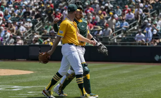 Athletics pitcher Hogan Harris, left, and catcher Willie MacIver, right, walk to the dugout during the seventh inning of a baseball game against the Philadelphia Phillies, Sunday, May 25, 2025, in West Sacramento, Calif. (AP Photo/Sara Nevis)