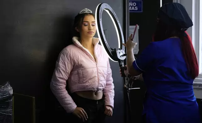 Quinceañera Helen Ibague poses for a stylist after having her makeup done for free, in Bogota, Colombia, Friday, May 2, 2025. The Sueños Hechos Foundation, led by a former police officer, is hosting a quinceañera celebration on Friday for 24 disadvantaged teen girls. (AP Photo/Fernando Vergara)