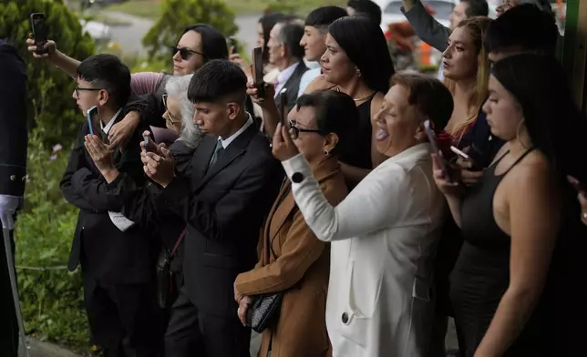 Relatives use their smart phone to record a group quinceañera celebration, in Bogota, Colombia, Friday, May 2, 2025. The Sueños Hechos Foundation, led by a former police officer, is hosting a quinceañera celebration on Friday for 24 disadvantaged teen girls. (AP Photo/Fernando Vergara)