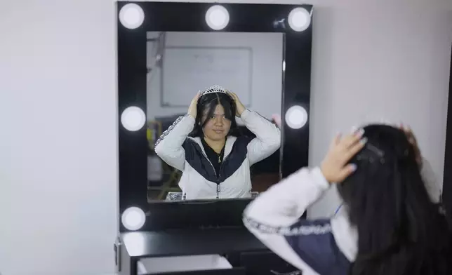 Quinceañera Sara Ariza adjusts her tiara as she waits to have her makeup done for free, in Bogota, Colombia, Friday, May 2, 2025. The Sueños Hechos Foundation, led by a former police officer, is hosting a quinceañera celebration on Friday for 24 disadvantaged teen girls. (AP Photo/Fernando Vergara)