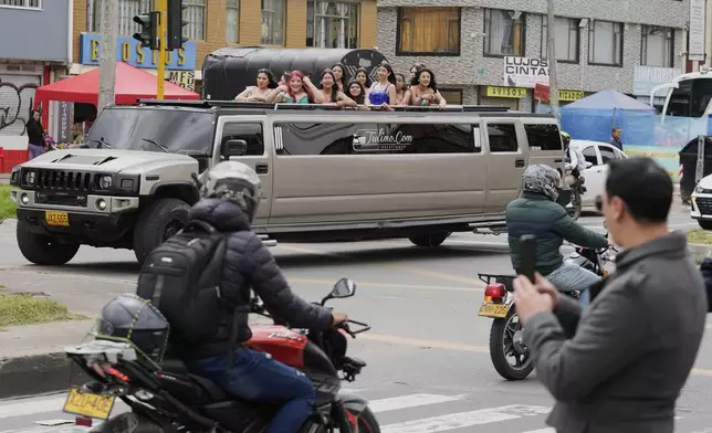 Quinceañeras ride in limousine as part of their celebration, in Bogota, Colombia, Friday, May 2, 2025. The Sueños Hechos Foundation, led by a former police officer, is hosting a quinceañera celebration on Friday for 24 disadvantaged teen girls. (AP Photo/Fernando Vergara)
