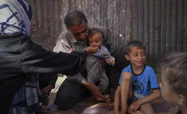 Wedad Abdelaal and her husband Ammar , feed their 9 month old son Khaled, in their tent at a camp for displaced Palestinians in Mawasi Khan Younis, Gaza Strip, Friday, May 2, 2025. (AP Photo/Abdel Kareem Hana)